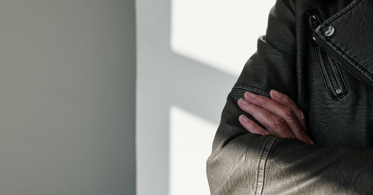 Close-up van een hand die voorzichtig een vastlopende rits van een jas losmaakt