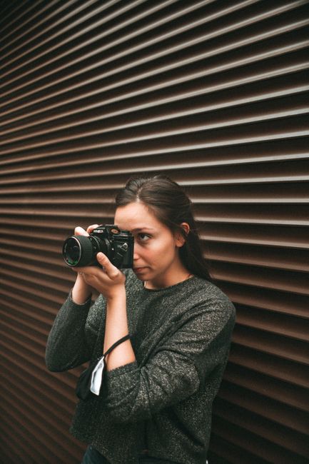 A woman photographer in Brussels capturing the urban landscape with her DSLR camera.