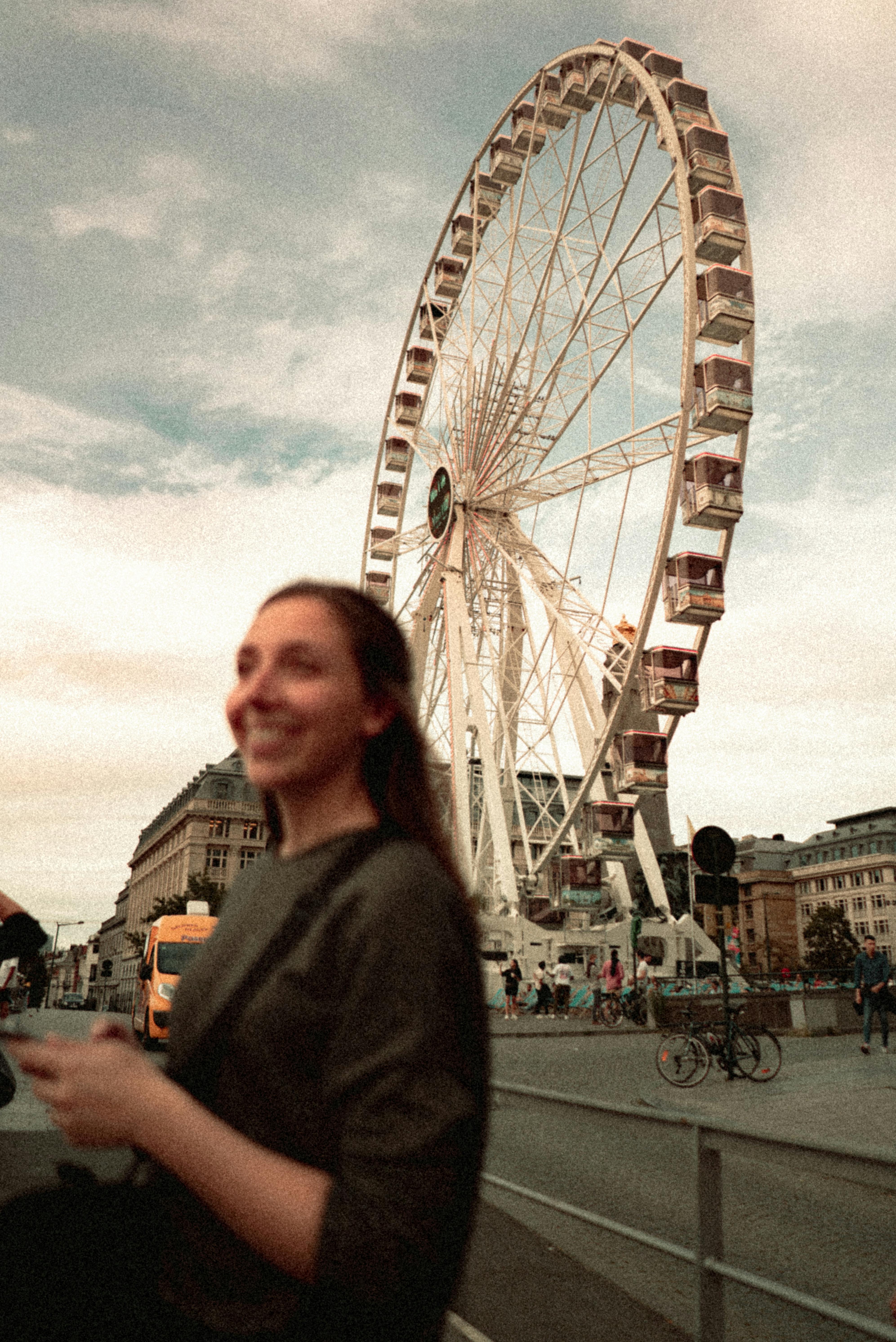 Smiling woman in front of a Ferris wheel at a Brussels fairground