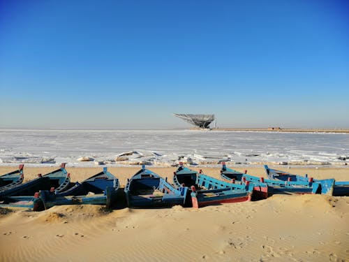 Ice Floes on Ocean and Blue Boats on Shore