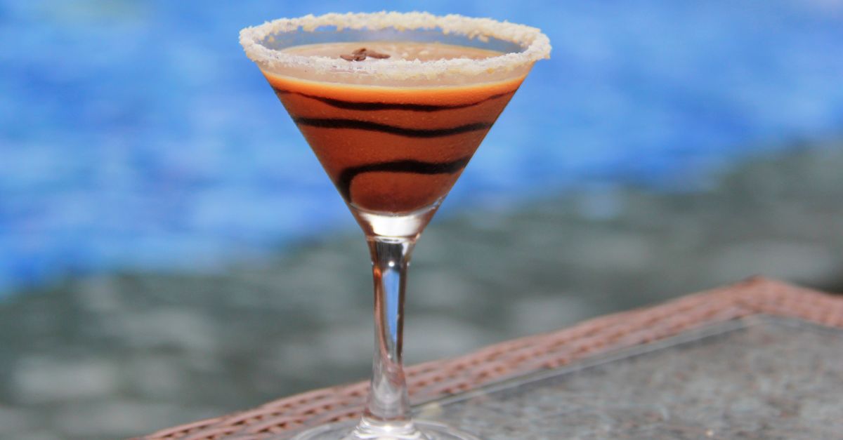 A decadent chocolate martini with a sugar rim beside a serene pool.