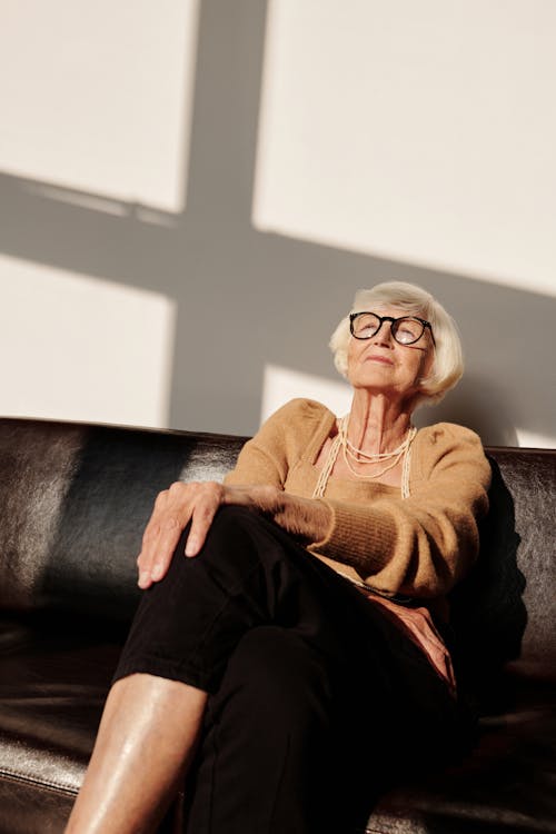 Woman in Brown Sweater Sitting on Black Couch