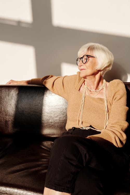Woman in Brown Sweater Sitting on Black Couch
