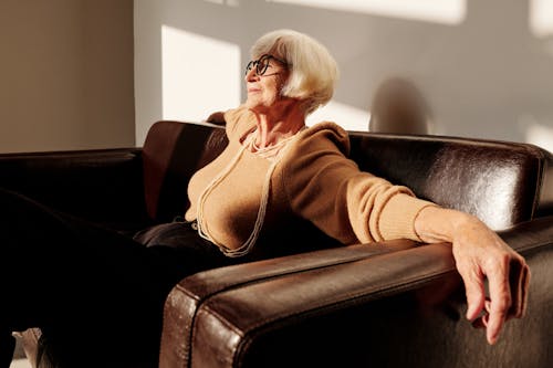 Woman in Brown Sweater Sitting on Black Couch