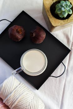 在舒适的公寓里，柔软的织物上摆放着一杯牛奶、石榴和一株多汁植物