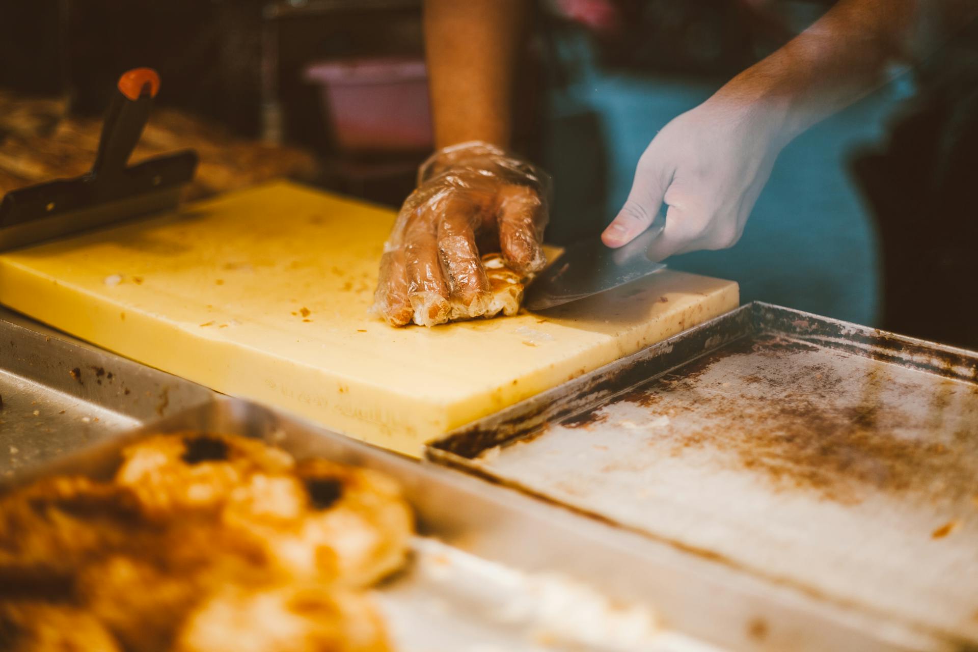 Close-up of a baker slicing fresh pastry with a knife, showcasing culinary craftsmanship.