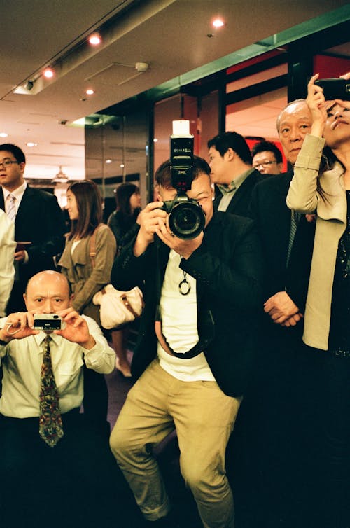 Free Group of Asian photographers with photo cameras taking pictures while working at crowded meeting Stock Photo