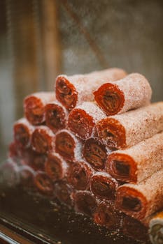Stack of sugared rolled pastries displayed indoors creating a mouth-watering treat.