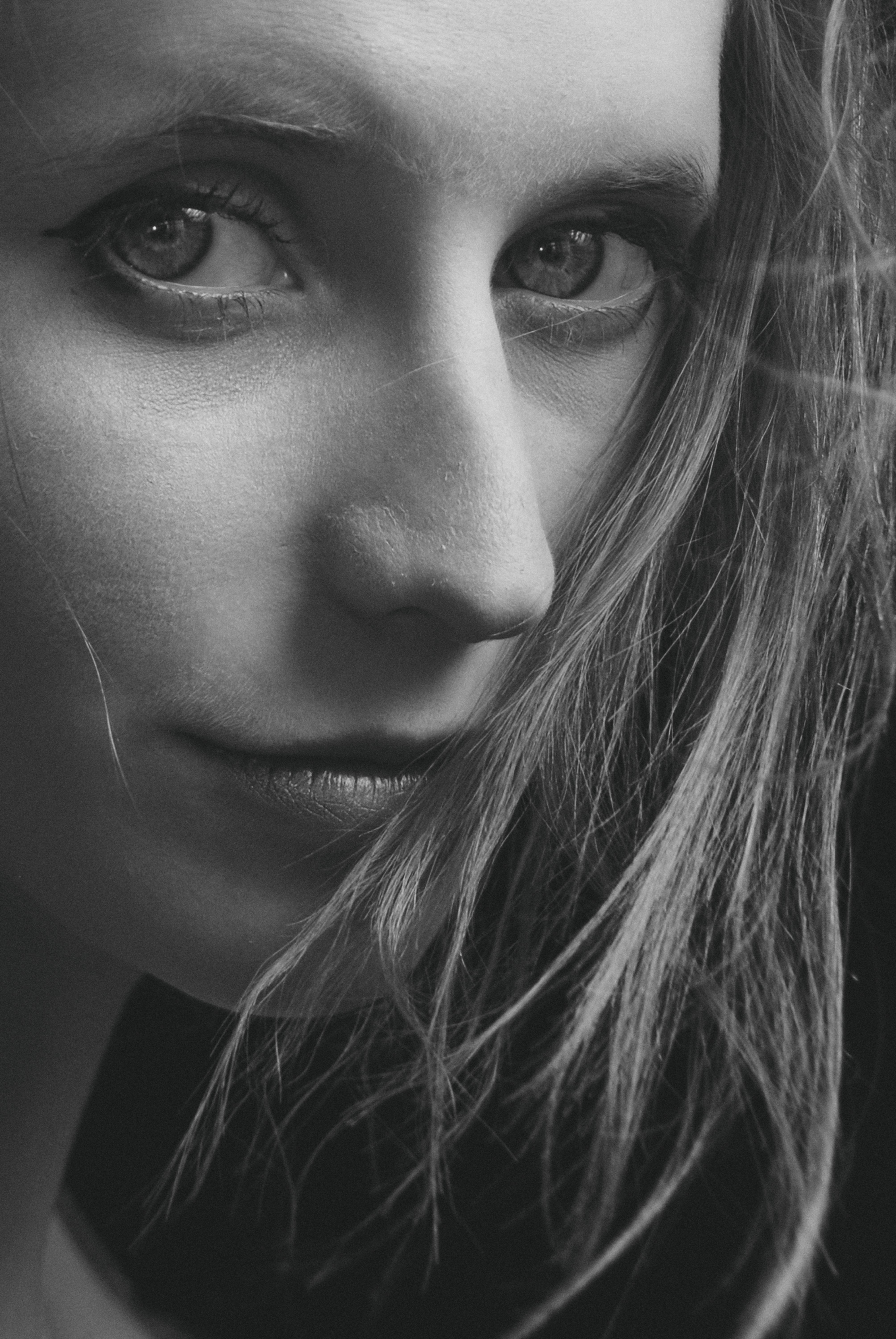 Striking grayscale close-up portrait of a woman's face, emphasizing her expressive eyes and natural beauty.