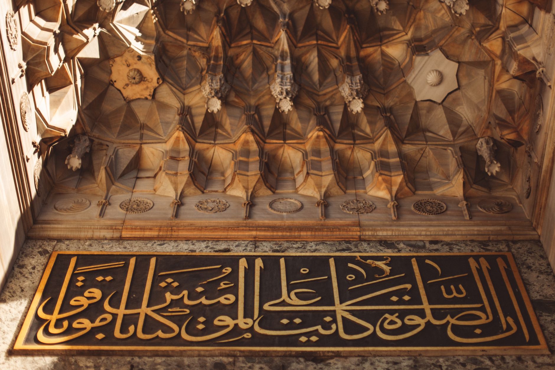 Stunning Arabic calligraphy on an ornate ceiling showcasing traditional Islamic architectural design.
