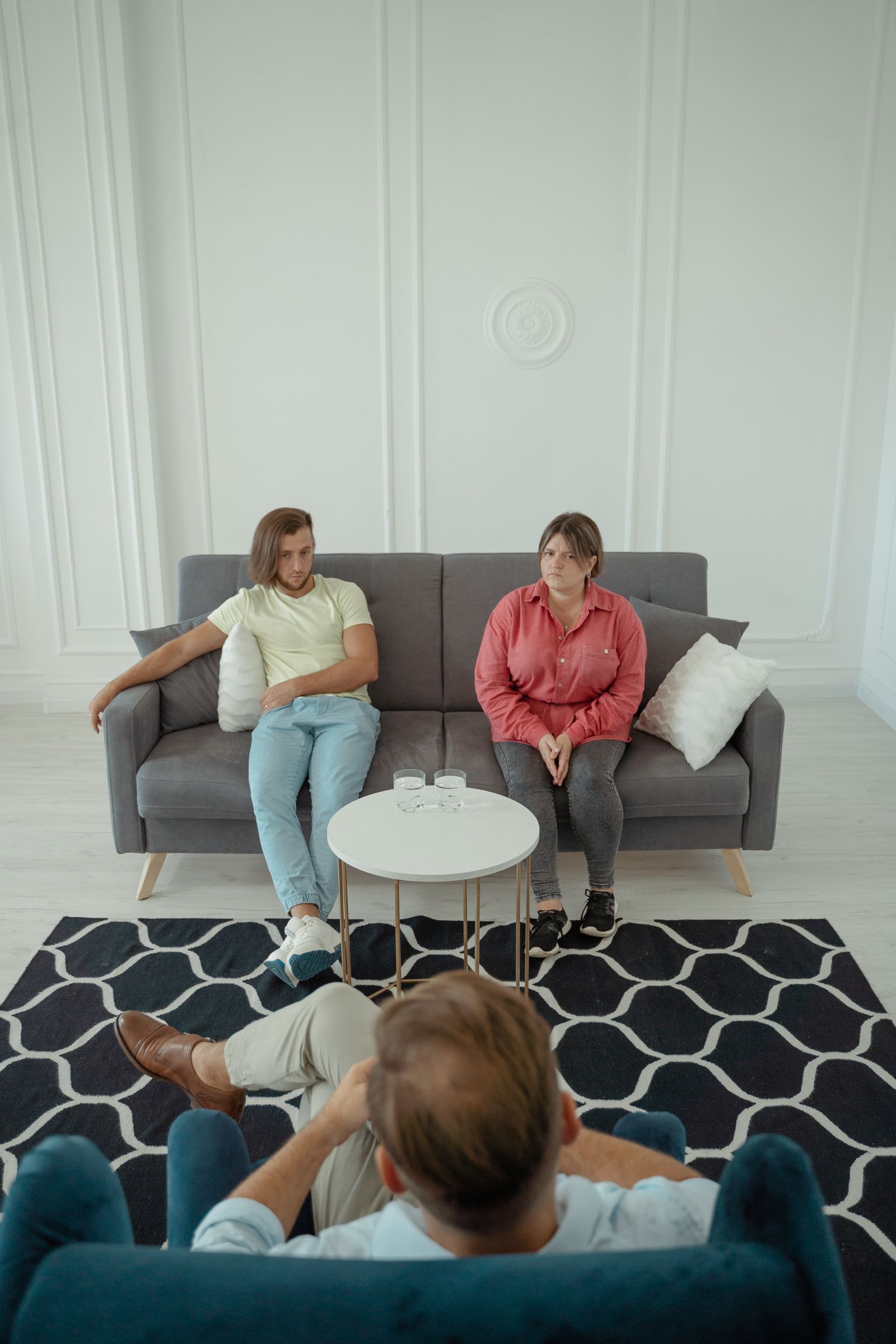 A couple sitting together on a sofa during a couples therapy session with a counselor