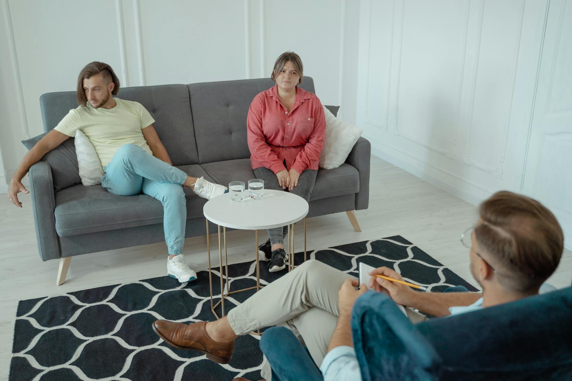 A couple attends a therapy session in a modern styled office setting, with a counselor sitting across from them.