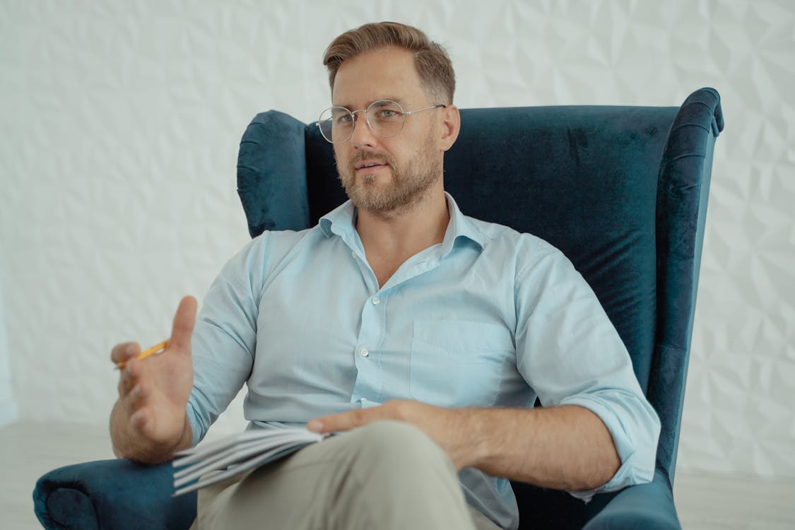 Free Man in Blue Polo Shirt Sitting on Blue Couch Stock Photo