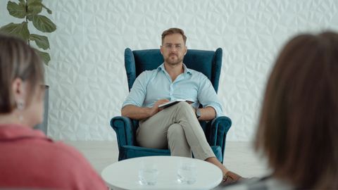 Therapist conducting a session with clients in a modern office setting. Focused professional atmosphere.