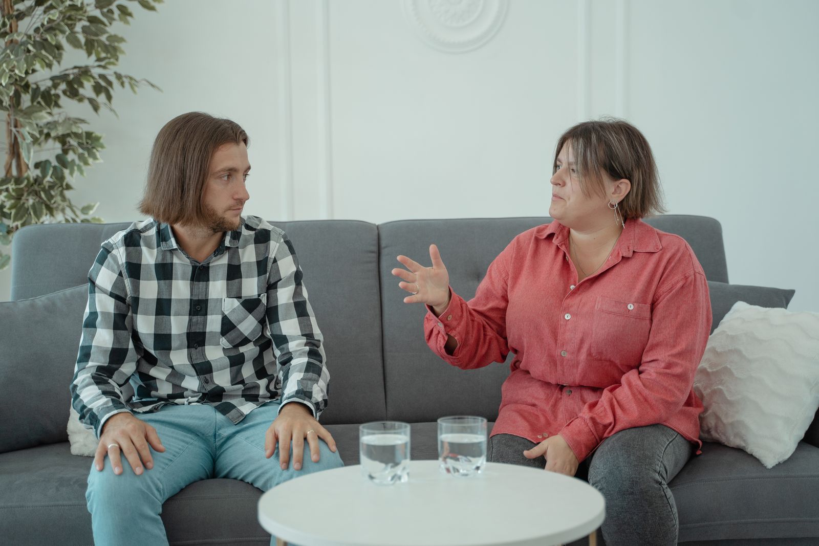 Two adults talking while seated on a sofa