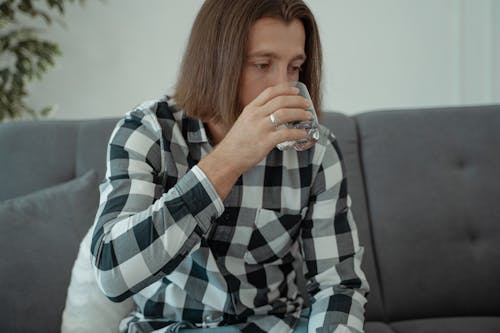 A Man in Checkered Shirt Drinking Water from a Glass