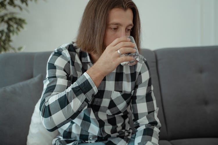 A Man In Checkered Shirt Drinking Water From A Glass