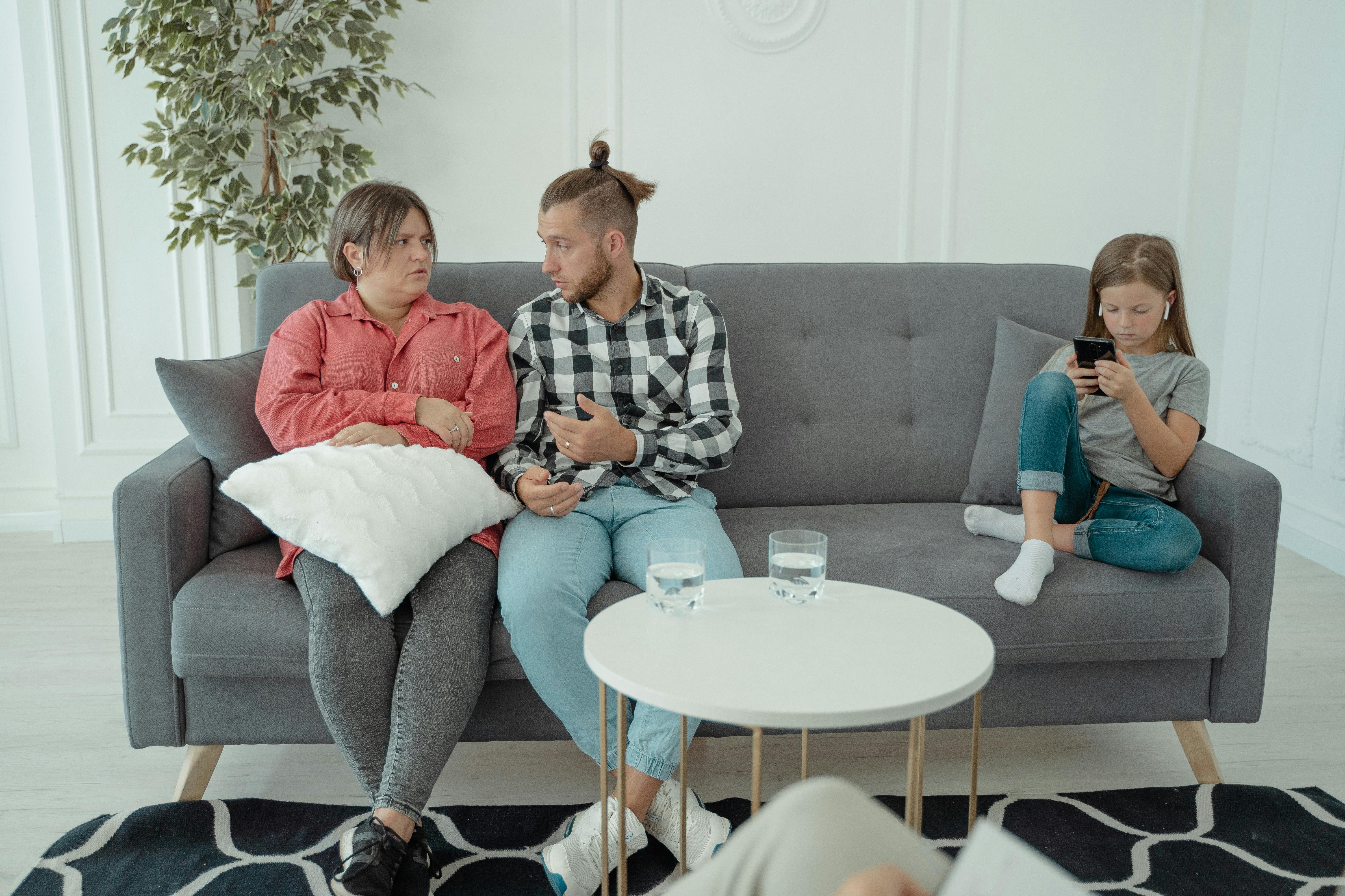 a couple sitting on a couch with their daughter at a therapy session