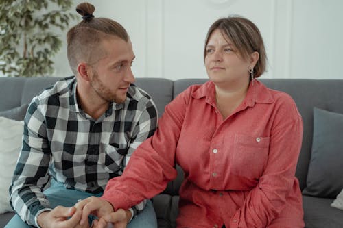 A Man and Woman Sitting on Couch Holding Hands