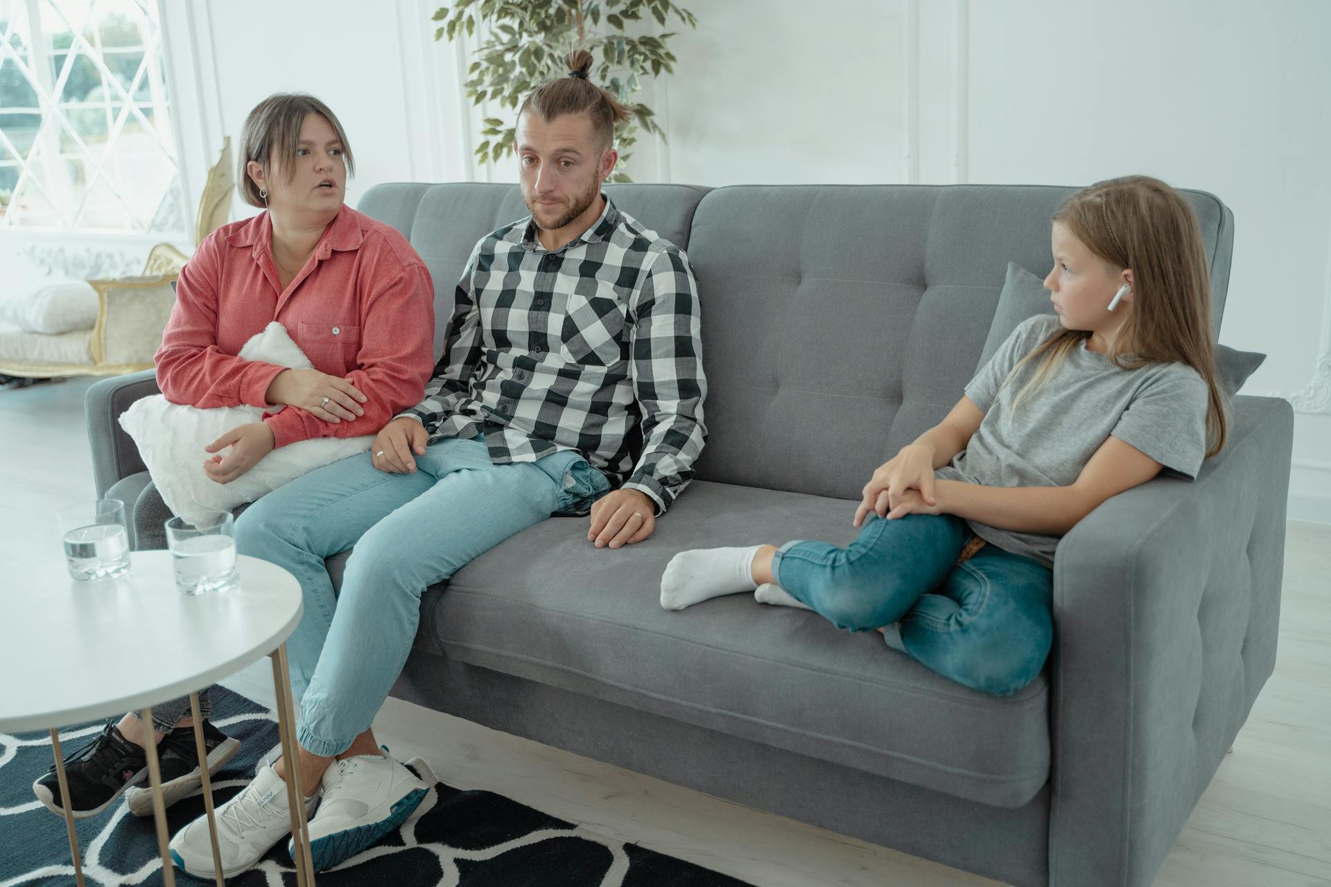 A family sits together on a sofa, discussing in a comfortable home setting, indicating a counseling session.