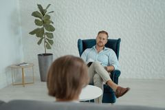 A counseling session with a man sitting in a comfortable chair indoors.
