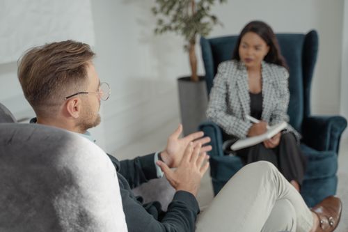 Free Two professionals engaged in a discussion in a modern interior with armchairs. Stock Photo