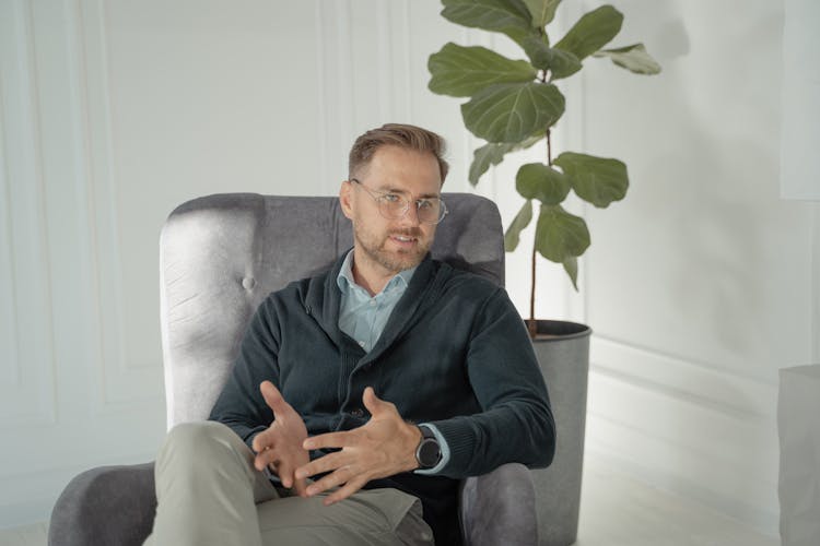 A Man In Gray Sweater Sitting On Armchair