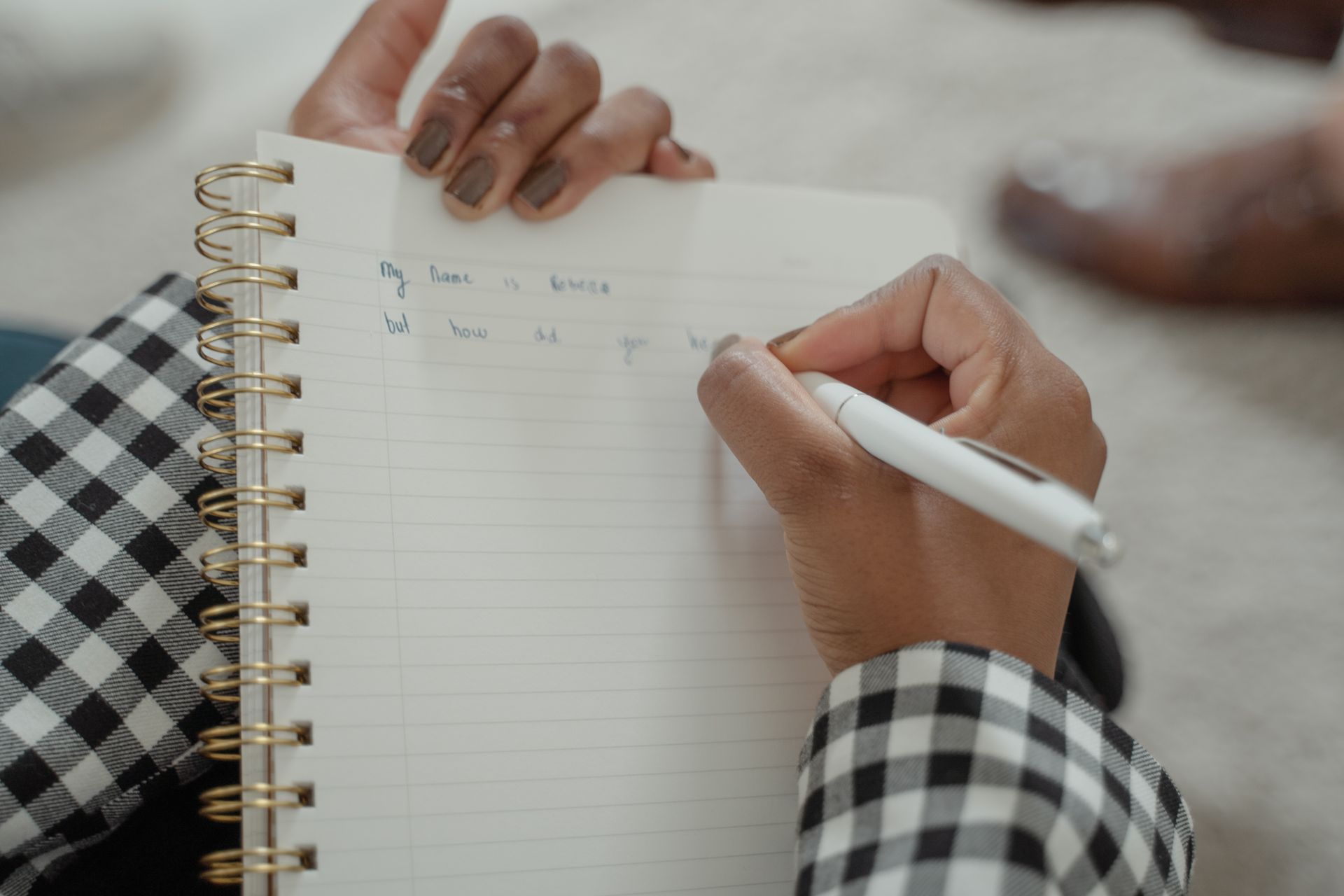 Close Up Photo of a Person Writing on a Notebook