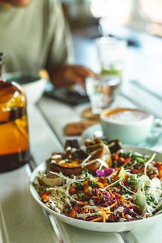 Vibrant vegan salad with diverse vegetables on a cafe table, perfect for a healthy lunch.