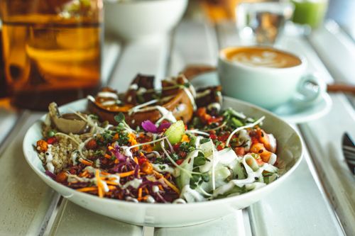 Free Colorful vegetarian salad with a latte on a white table, captured in a cozy indoor setting. Stock Photo