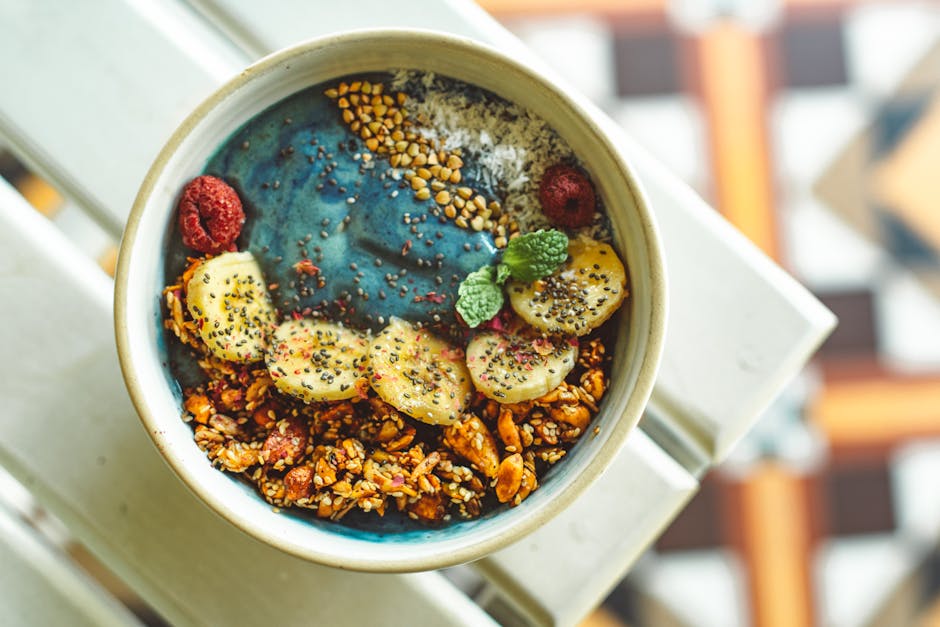 Vibrant blue spirulina smoothie bowl topped with bananas, granola, and berries for a nutritious meal.