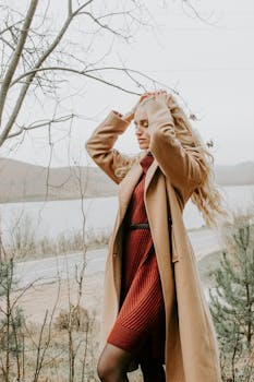 Blonde woman in a fashionable coat and dress outdoors in Minsk, showcasing fall style.