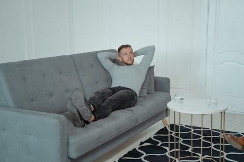A Man Sitting on a Couch with his Legs up