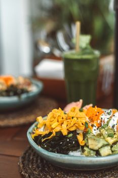 A colorful and vibrant close-up of a healthy Asian cuisine bowl paired with a green smoothie.