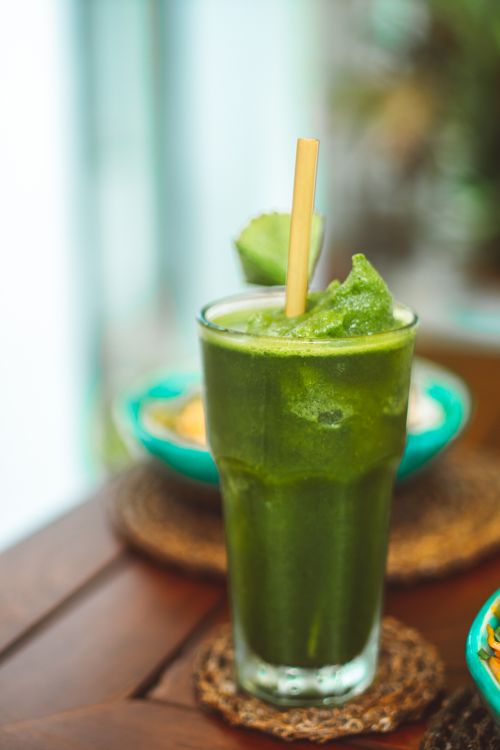 Free Fresh and healthy green smoothie with bamboo straw on a wooden table, ideal for a refreshing drink. Stock Photo