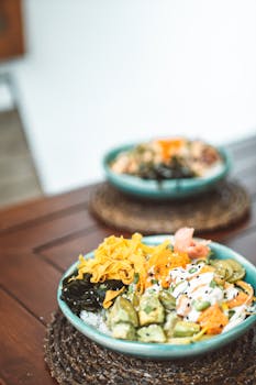Colorful poke bowl with fresh vegetables and proteins on wooden table, emphasizing healthy eating.