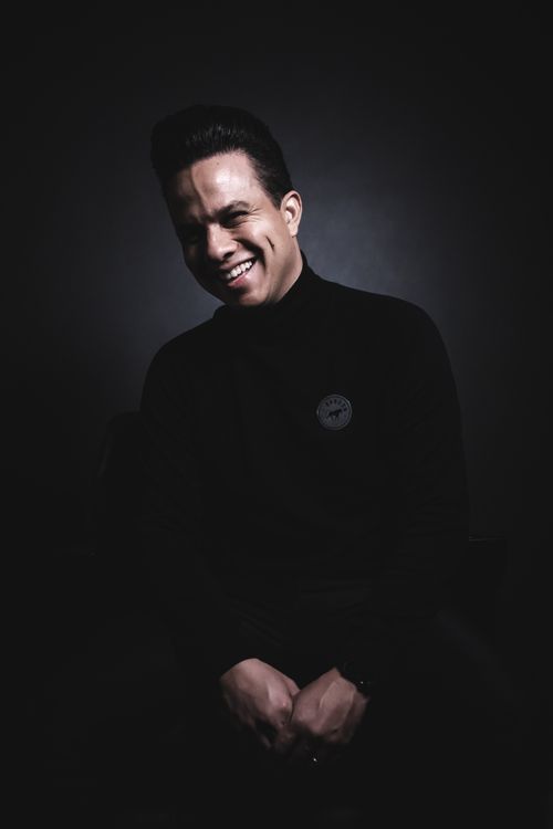 Free Portrait of a smiling man in a black turtleneck against a dark background. Stock Photo