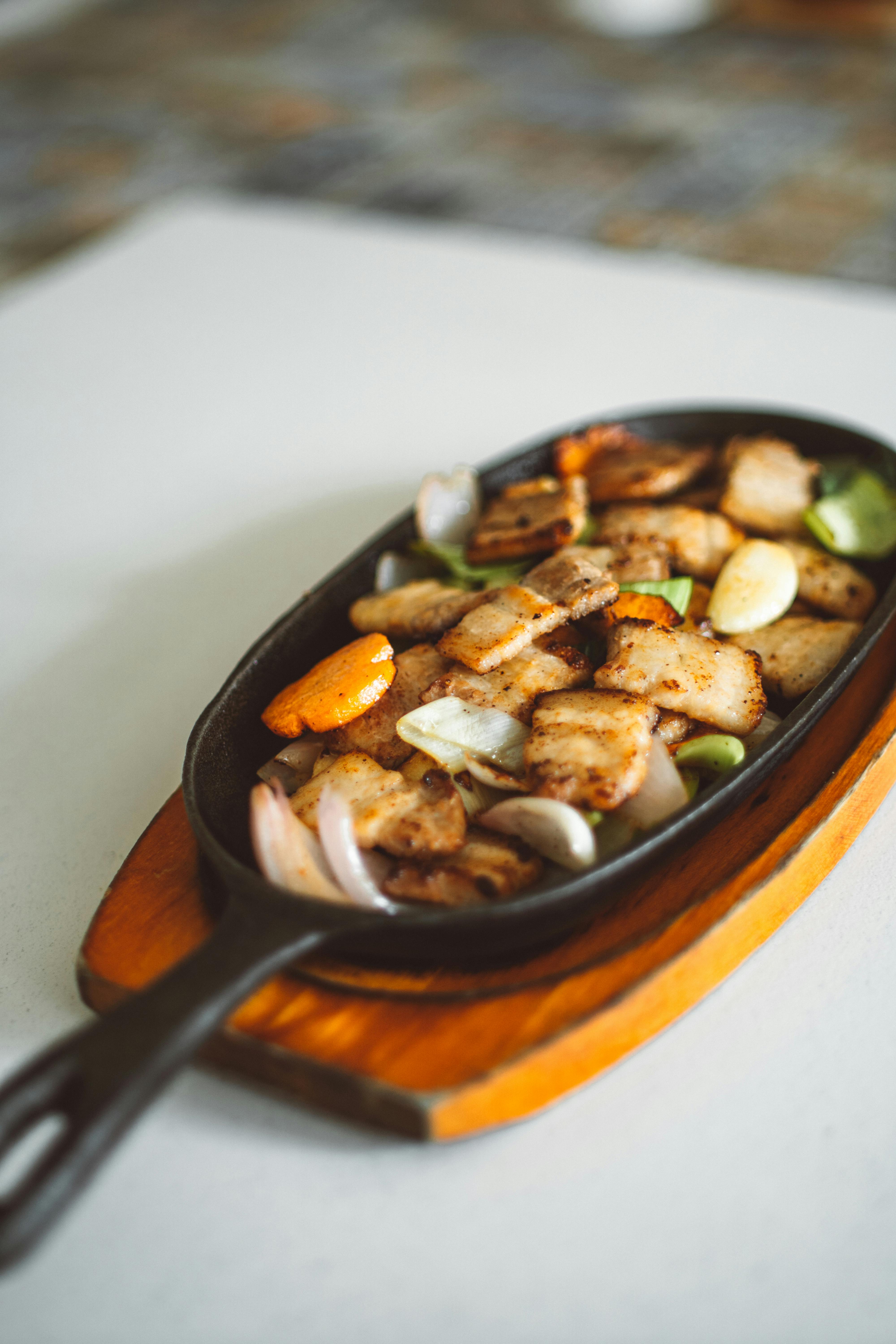 cooked meat and vegetables on a cast iron pan