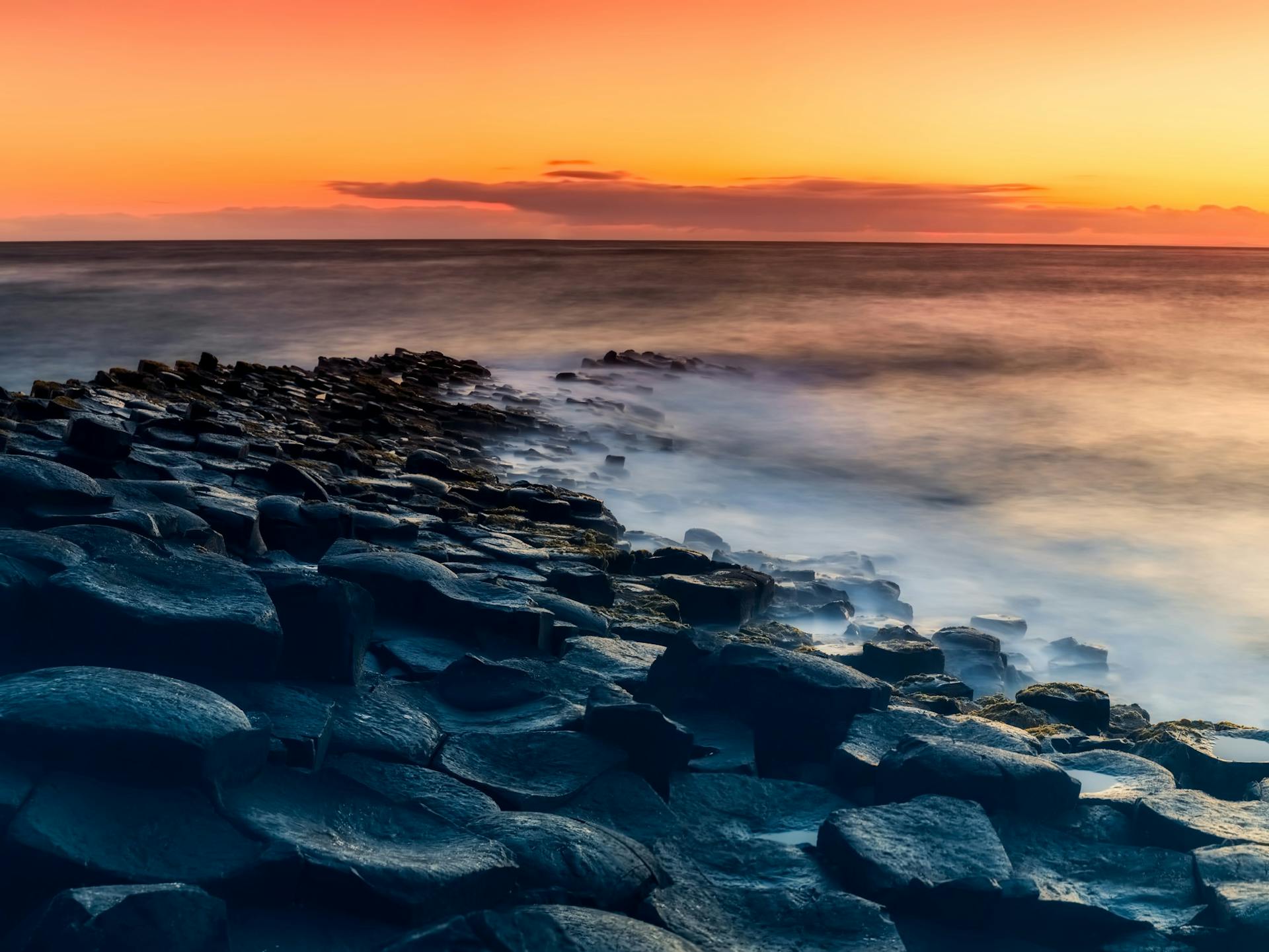 Enchanting sunset view over the Giant's Causeway with dramatic skies and ocean waves.