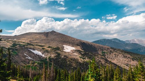 Free Stunning view of a mountain range with fluffy clouds and lush pine trees, perfect for nature lovers. Stock Photo