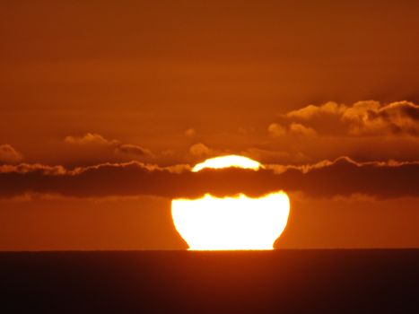 A captivating sunset with clouds casting shadows over the horizon, creating a stunning silhouette.