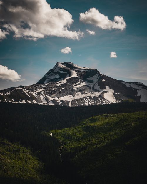 Free Stunning view of a snow-capped mountain with vibrant green landscapes under a clear blue sky. Stock Photo