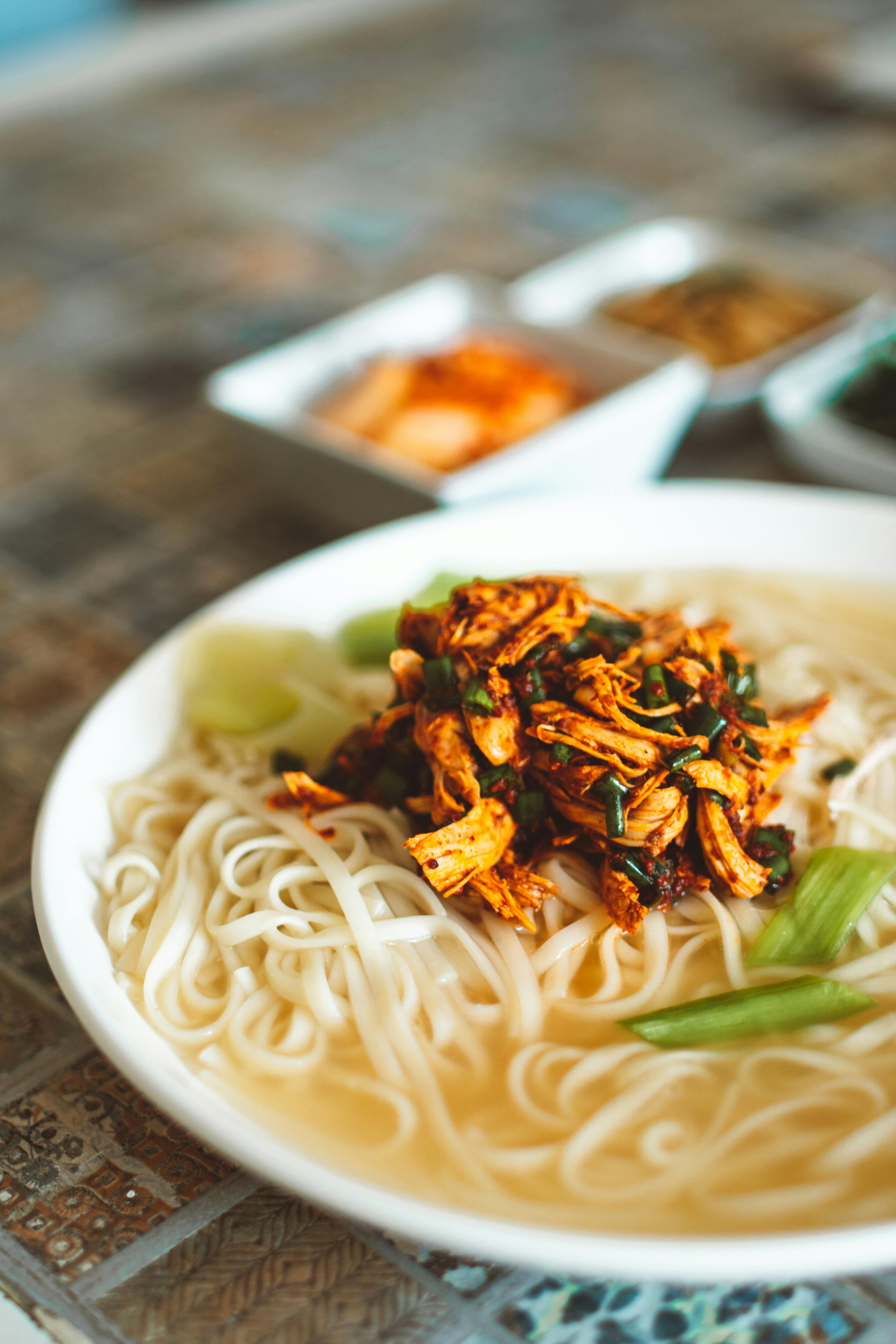 a delicious noodle soup topped with shredded chicken and scallions