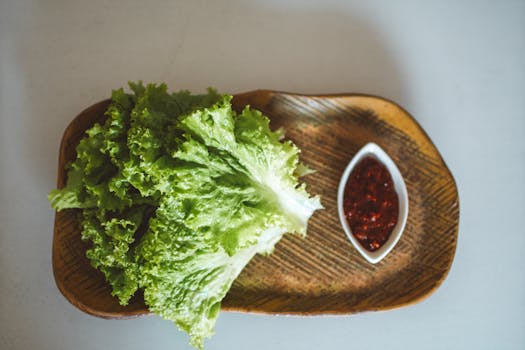 Top view of crisp lettuce and spicy sauce on a wooden plate, perfect for organic meals.