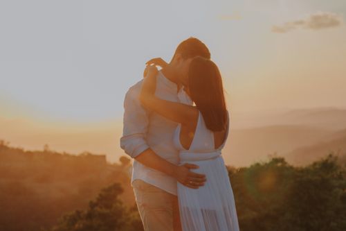Free A couple shares a romantic embrace against a stunning sunset backdrop, symbolizing love and togetherness. Stock Photo
