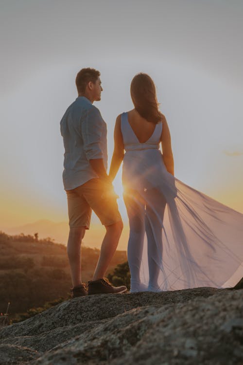 Free A Couple Holding Hands Against the Sun Stock Photo