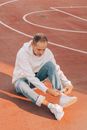 Trendy man rolling up jeans on sports ground