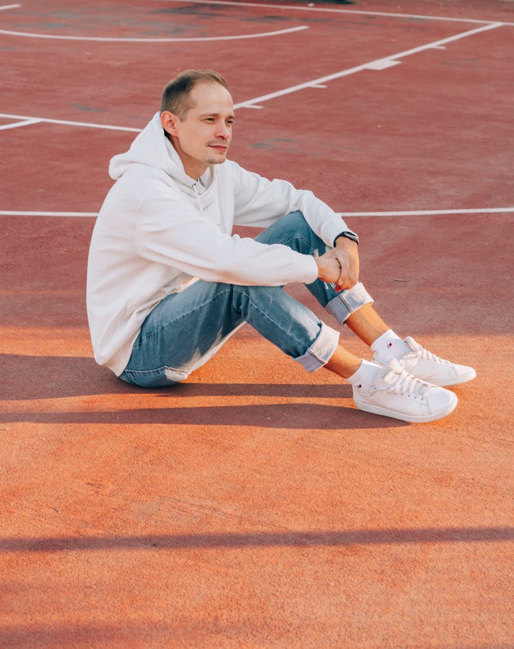 Contemplative Man In Trendy Outfit Resting On Sports Ground