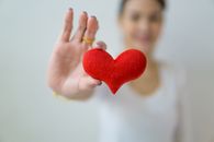 一位手持红心的女人特写，象征着爱、关怀与健康
