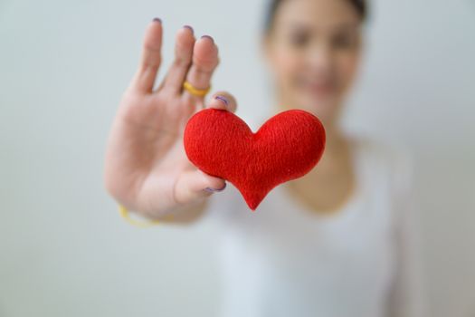 一位手持红心的女人特写，象征着爱、关怀与健康